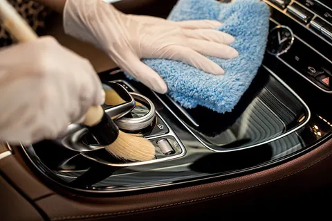 Detailer applying leather conditioner to car seat